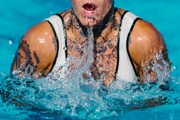Female with tattoos swimming breaststroke