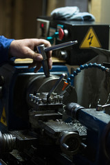 Metalworking. Man working on a small lathe machine in a craftsman workshop. 