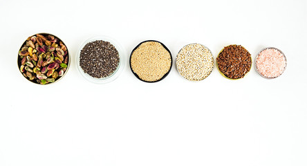 Various superfoods on a white background. Pistachio nuts, chia seeds, amaranth, quinoa, flex seeds, rose salt. Copy space for text