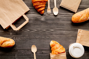 cup coffee and bread in paper bag on wooden background