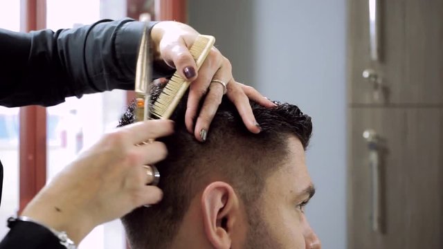 Haircut at barber's. Female hairdresser shaping men's hair into a style by cutting. HD