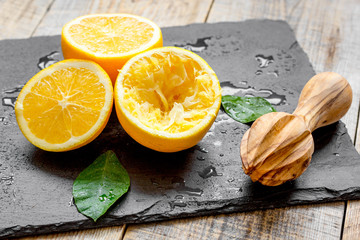cut oranges in half and juicer on wooden background
