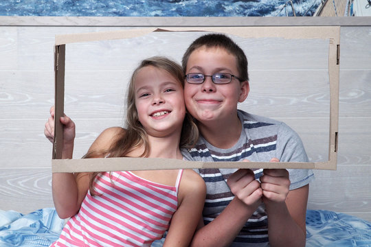 Cute little boy and girl are posing together holding a portrait frame