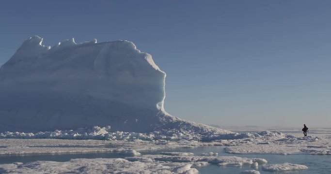 Pan with photographer in distance walking across sea ice