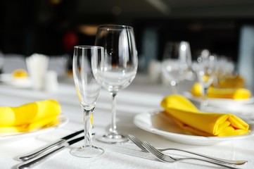 beautiful empty wine glasses and yellow napkin on a decorated table close-up.