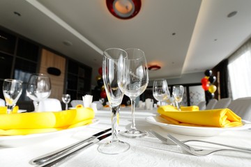 beautiful empty wine glasses and yellow napkin on a decorated table close-up.