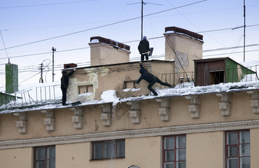 Take off the snow and icicles from the roof. Working cleaning work without insurance. Russia, St. Petersburg