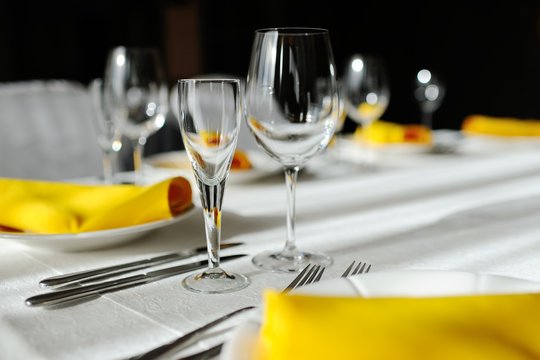 beautiful empty wine glasses and yellow napkin on a decorated table close-up.
