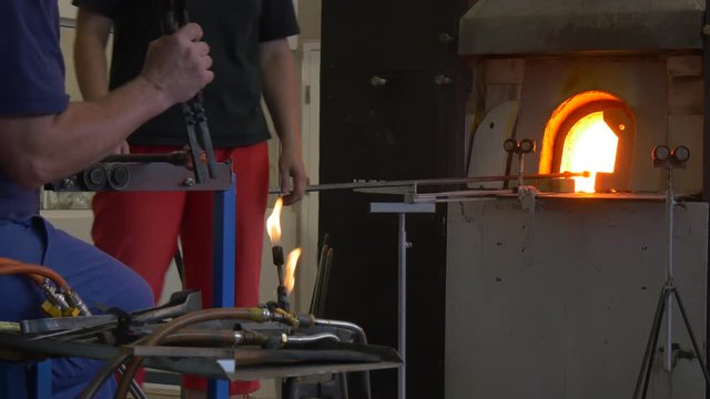 Two Glassblowers Heating Parts of Glass Sculpture in Furnace Festival of High Temperatures People Show Their Skills Glassworks Craftsmen in Workshop