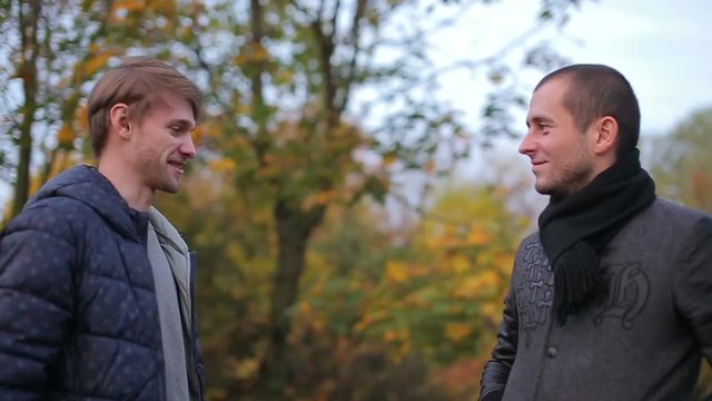 two male friends giving high-five during luch break in autumn park