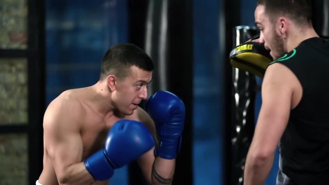 Boxer training uppercut punches in boxing club HD slow motion video. Fighter practices blows with trainer punch mitts. Combat sport technique