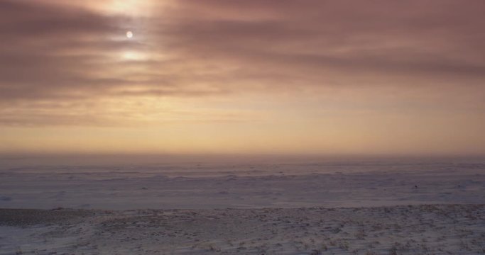 Wide clouds flow past afternoon sun during tundra ground blizzard