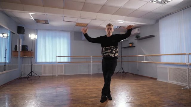 Young dancer in a dance perform complex motion. Professional dance studio. Handsome guy rehearsing their dance before the show.