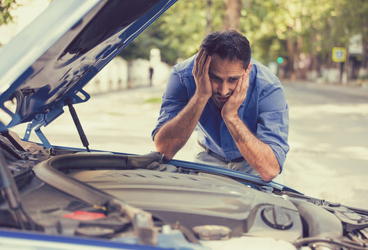 stressed man with broken car looking at failed engine