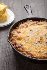 Close up of homemade chili baked in cast iron skillet with side of cornbread