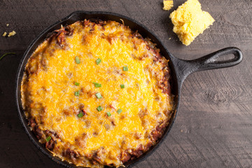Above view of homemade chili baked in cast iron skillet with layer of fritos on bottom.