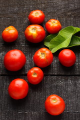 Fototapeta na wymiar Organic fresh tomatoes on a dark wooden background,