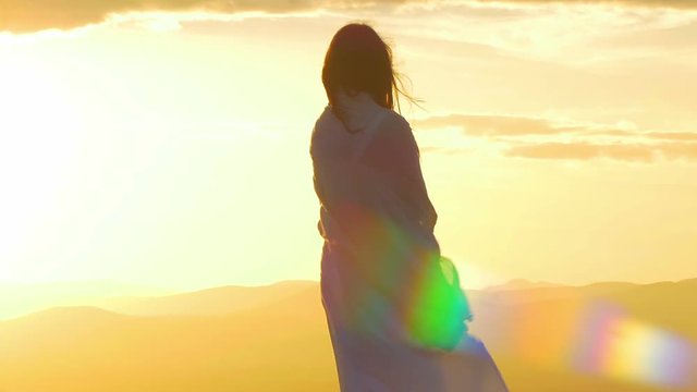 beautiful woman at the sunset on the top of a mountain with lens flare