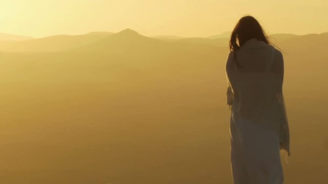 beautiful woman at the sunset on the top of a mountain: windy sunset
