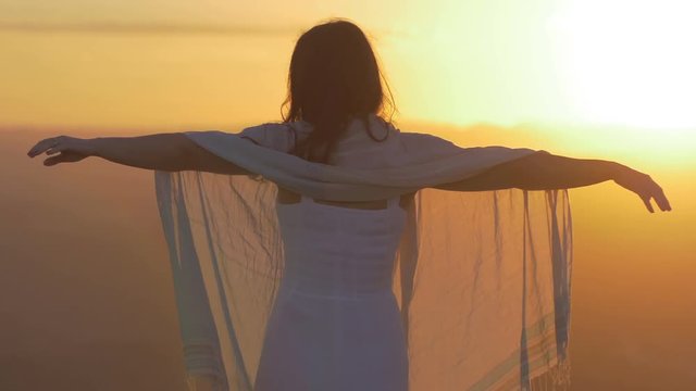 relaxing beautiful woman  contemplates the sunset on top of a mountain