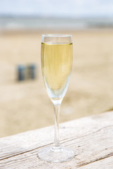 Champagne glass on a wooden table with beach background