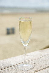 Champagne glass on a wooden table with beach background
