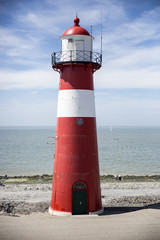 Fototapeta premium Red and white lighthouse on a blue sky background, Westkapelle, The Netherlands