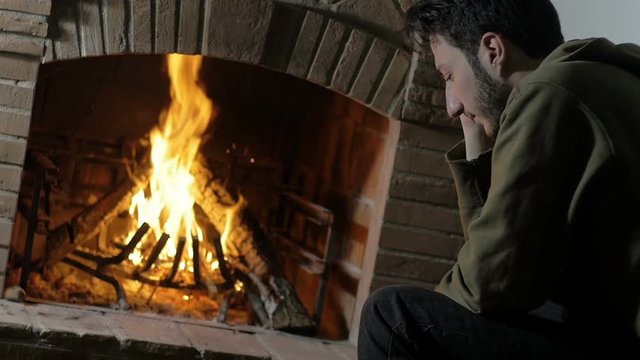 in chrstimas time a man alone at home sat near a burning fire, back view, home