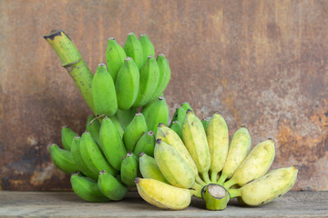 Bunch of ripe bananas and raw banana on wood background
