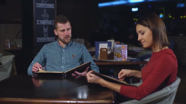 beautiful couple at the dinner in the restaurant looking menu