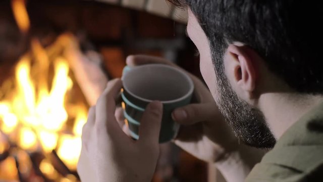 in chrstimas time a man alone at home sat near a burning fire, back view, home