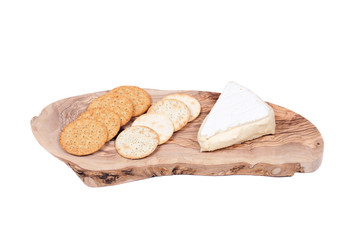 Supremely creamy soft ripened brie cheese and wheat crackers on olive wood cutting board isolated on white background
