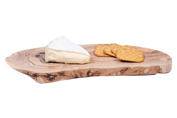 Supremely creamy soft ripened brie cheese and wheat crackers on olive wood cutting board isolated on white background