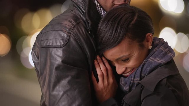 A black couple embrace each other on a busy city street