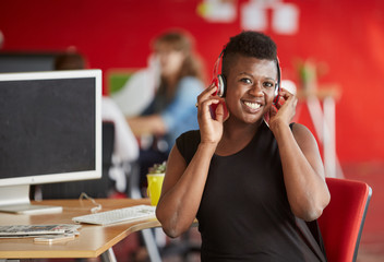 Confident female designer listening to music in red creative office space