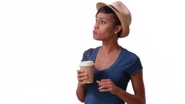 An African American woman drinks coffee and eats a pastry on a white background