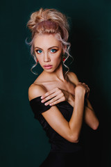 Cute young blonde with blue eyes in black dress. Background in t