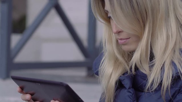 young woman using tablet pc sitting on the stairs of St. Peter square in Rome