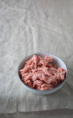 Raw ground pork in a  ceramic bowl. Linen background 