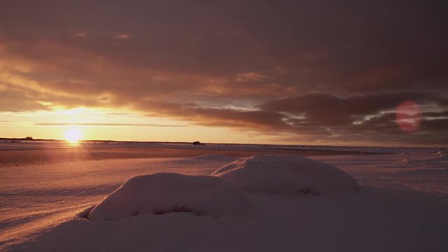 Scenic sunset pan across arctic snow with clouds and golden light