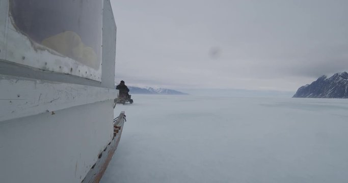 Next to komatik speeding over sea ice on stormy day