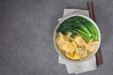 A bowl of Hong Kong style wonton soup, Dark gray background. Copy space 