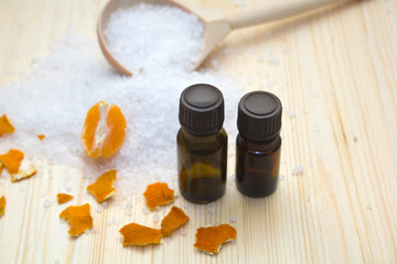 sea salt in wooden spoon, aroma oil, peel and slice citrus on wooden background. Spa concept.