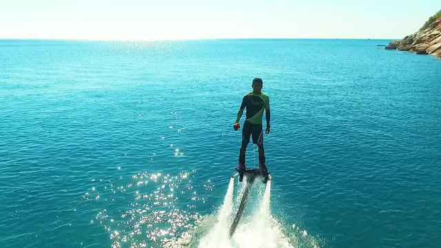 Aerial: Man climbs out of the water on flyboard.
