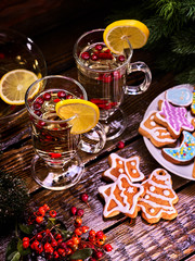 Three Christmas cookies in shape of stars and gingerbread Christmas trees. Nearby are mugs with hot tea and lemon.
