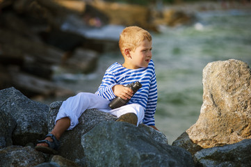 little boy with binoculars , the sea in the background