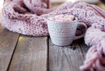 Fototapeta na wymiar coffee mug with marshmallows in front of a knitted scarf