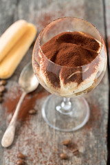tiramisu in a vine glass on wooden surface