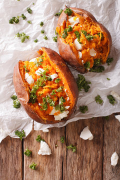 sweet potatoes baked with feta cheese and parsley on the table. vertical top view
