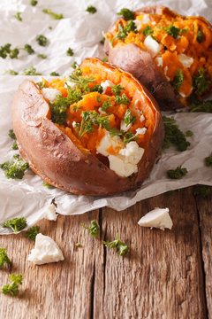 Delicious baked sweet potatoes stuffed with feta cheese and parsley close-up. vertical